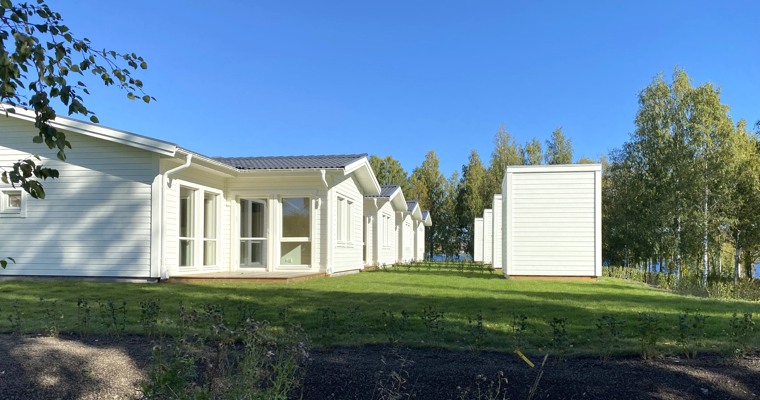 vita nybyggda hus vid en grön gräsmatta och blå himmel
