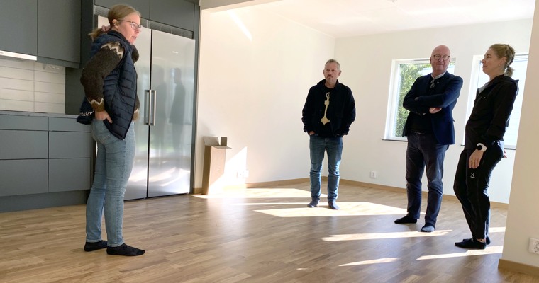 Fyra personer står i ett omöblerat rum i ett nybyggt hus