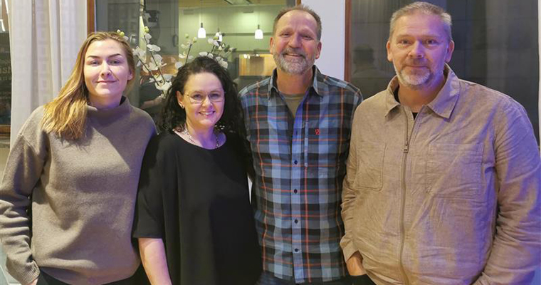 Fyra personer står tillsammans leeende