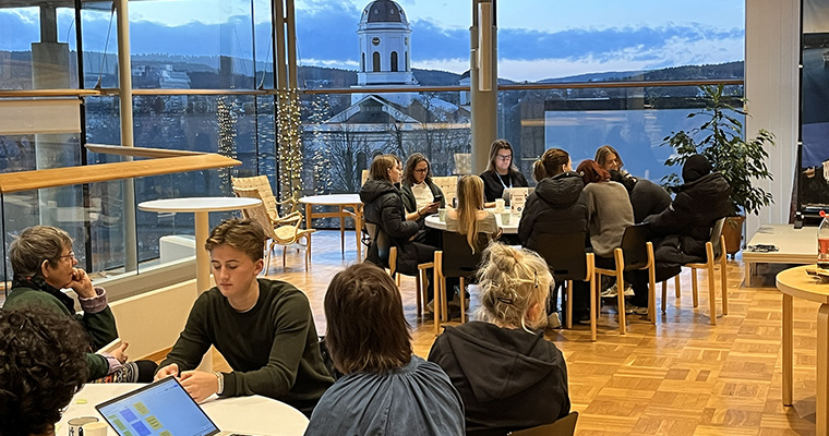 Ungdomar och vuxna sitter kring runda bord och samtalar