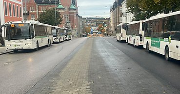 flera bussar står uppradade vid hållplatsen i centrum intill rådhuset