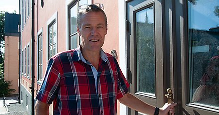 en man står vid en dörr med handen på dörrhandtaget.