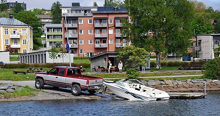 bil med båtvagn på släp. Båtvagnen står halvvägs nere i vattnet på en sjösättningsramp