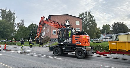 en grävmaskin i arbete mitt på en gata