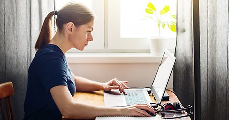kvinna sitter vid ett bord med en laptop framför sig