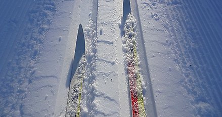 ett skidspår fotograferat uppifrån. I spåret syns två skidspetsar.