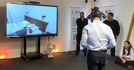 En man med VR-utrustning tittar på en skärm med en datoranimerad figur.