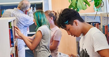 Lärare och elever i ett skolbibliotek