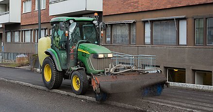 en traktor sopar upp grus på en trottoar