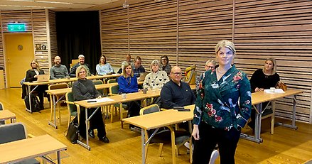 En föreläsare som står i en föreläsningssal framför ett tiotal kursdeltagare.