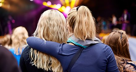 Två oidentifierbara tjejer tittar på en konsert.