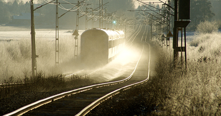 tåg som rullar på rak järnväg i lite dovt ljus