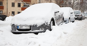 insnöade parkerade bilar längs en gata