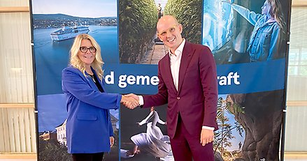 En man och en kvinna skakar leende hand.