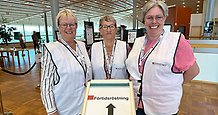 tre kvinnor i vita västar står bakom en skylt där det står förtidsröstning