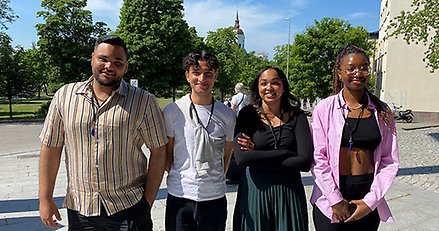 Fyra leende ungdomar poserar framför Stadsparken med domkyrkan i fonden.