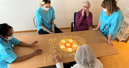 Personal och boende spelar Tovertafel, ett spel som stimulerar aktivitet.