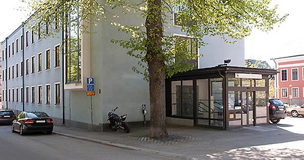 Stadshuset från utsidan. Ljusblå stenhus med putsfasad. Kommunvapnet på fasaden.