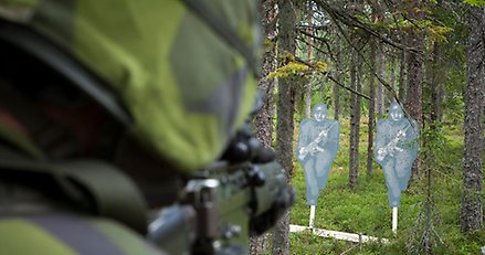 soldat sedd bakifrån som siktar på två silhuetter av människor