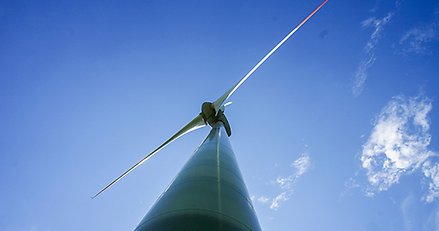 vindkraftverk fotograferat nedifrån med blå himmel i bakgrunden