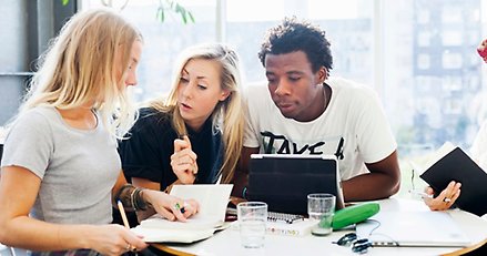 Tre studenter diskuterar i grupp.