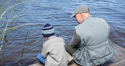 Genrebild av barn och äldre man som sitter på en brygga och fiskar.