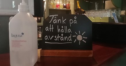 Skylt som säger håll avstånd och handsprit bredvid