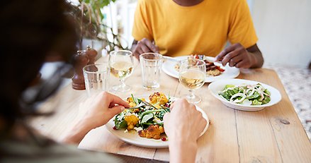 Två personer äter middag på restaurang, över axeln vy över bordet de sitter vid