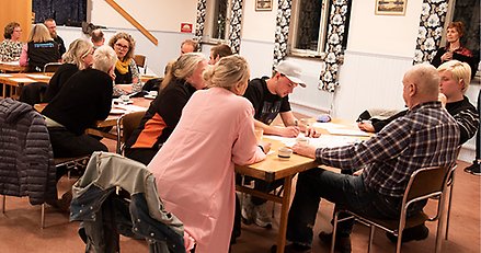 Människor diskuterar och antecknar under ett stormöte.