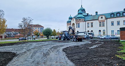 ett parkområde som renoveras. I centrum står en stor grävmaskin och i bakgrunden ett stort och gammalt hus.