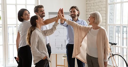 fem personer står i en ring och gör en gemensam high-five