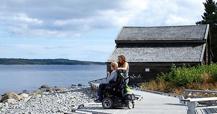 Två personer intill havet vid Sälsten. Den ena är rullstolsburen.