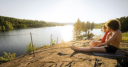 två personer på solvar klippa intill badsjö