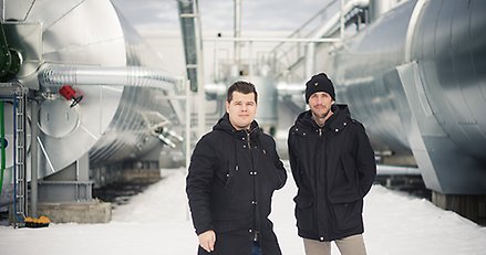 Två män framför en anläggning för biogas