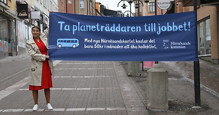 kvinna håller upp en bamderoll med texten "Ta planeträddaren till jobbet"