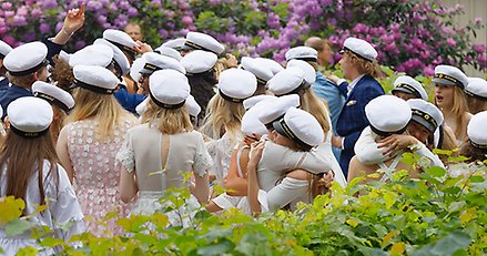 Studenter utomhus med studentmössor. 