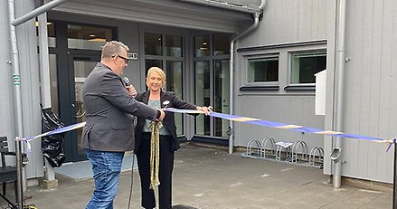 Invigning av boende. En man klipper symbolisk ett band som en kvinna håller i.