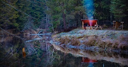 å i skog som rinner förbi ett vindskydd när vi ser två personer