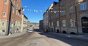 en stadsgata med ett flaggspel mellan husen