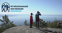 Ett äldre par står på ett berg och tittar ut över havet.