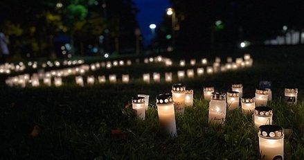 Många gravljus står tända i en park kvällstid.