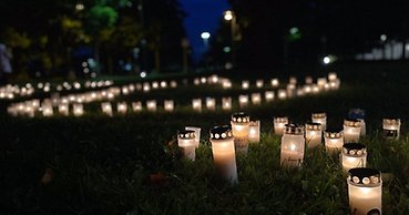 Många gravljus står tända i en park kvällstid.
