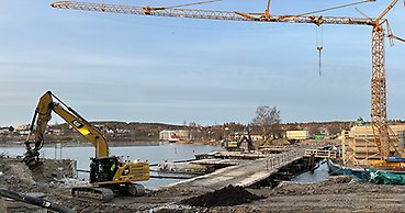 en byggarbetsplats med bland annat en grävmaskin och en stor kran