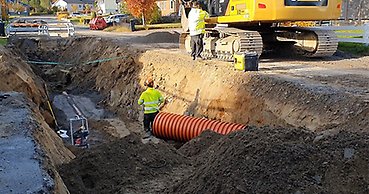 En arbetande person står vid ett stort rör. 