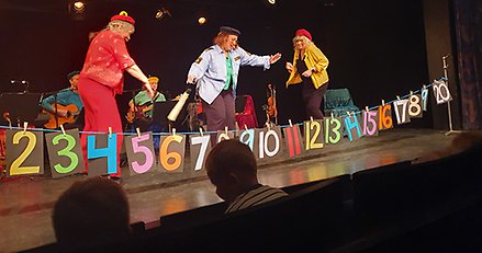 Tre vuxna spelar teater på en scen.