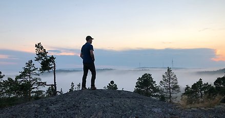 en silhuett av en person som står på en bergstopp med en kvällshimmel i bakgrunden