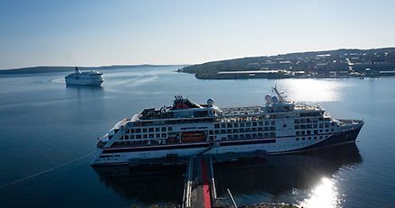 Två kryssningsfartyg i Härnösands hamn. Ett ligger vid kaj och ett är på väg in.