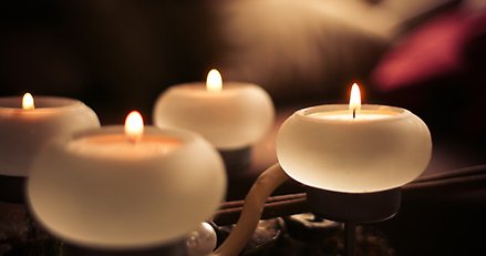 Fyra små ljuslyktor med brinnande värmeljus i.