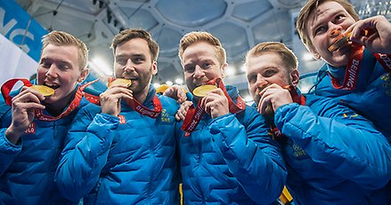 fem män i blåa jackor biter i varsin medalj
