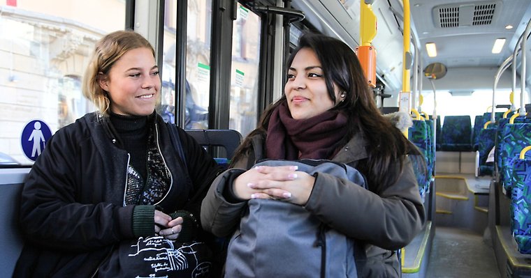 två unga kvinnor sitter bredvid varandra på en buss